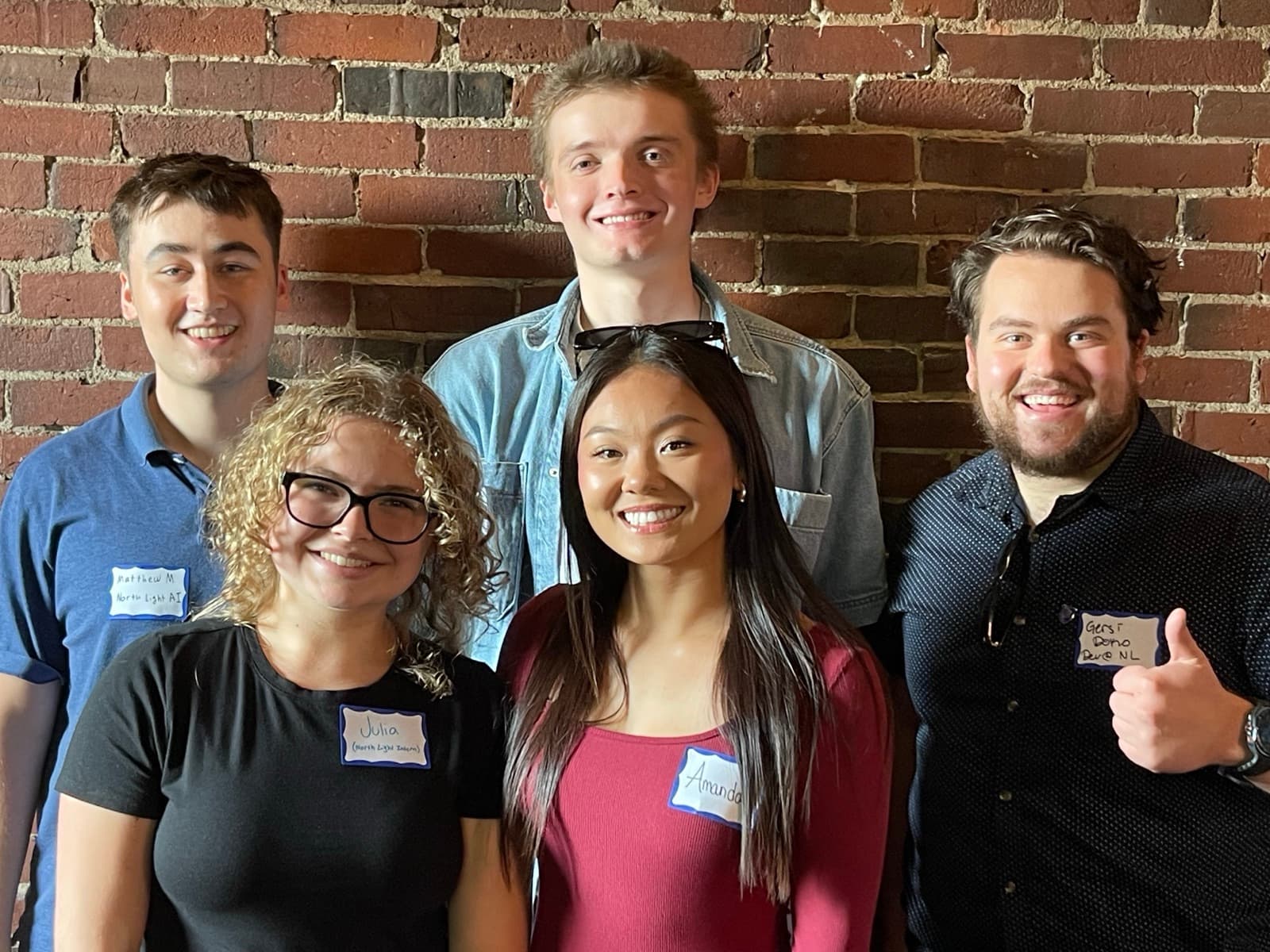 The North Light team and summer interns against a brick wall